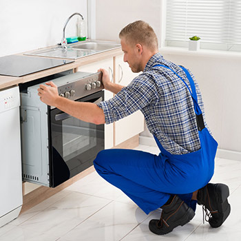Techniker schiebt Elektroofen zurück in die Einbauküche