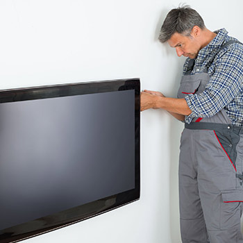 Techniker schraubt an der Rückseite eines Flachbildschirms