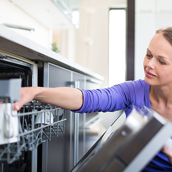 Frau kontrolliert eine Tasse im Geschirrspüler