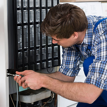 Fachmann schraubt an der Rückseite eines Kühlschranks