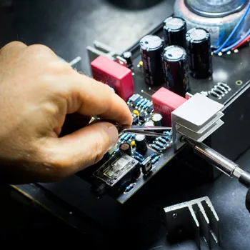 Eine Hand die eine Platine repariert